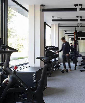 A man is walking past a row of exercise bikes in a gym.