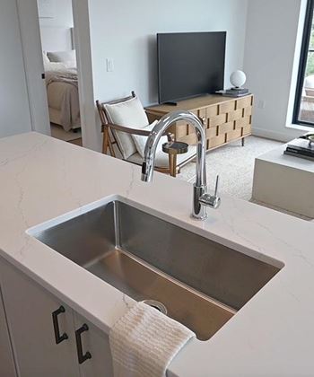 A modern kitchen with a stainless steel sink and a white countertop.