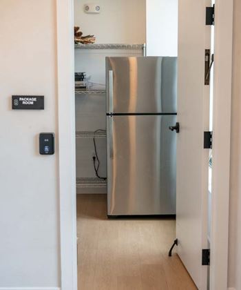 A stainless steel refrigerator is in a kitchen next to a door.