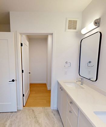 A bathroom with a sink, mirror, and wooden floors.