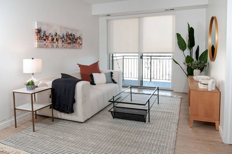A living room with a white couch, a coffee table, and a painting on the wall.