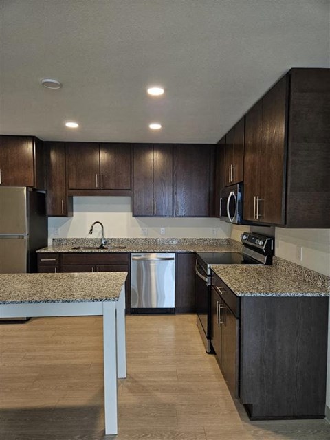 A kitchen with dark wood cabinets and a granite countertop.