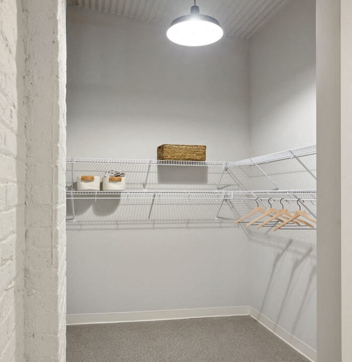 a white wire shelving unit in a white room with a white brick wall