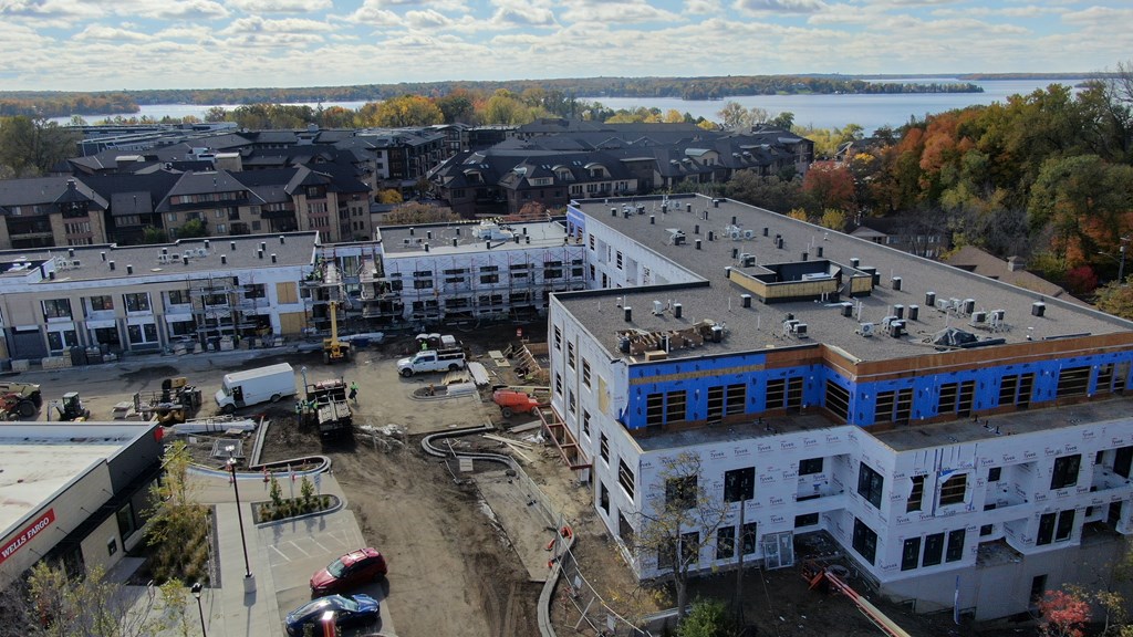 A construction site with a building under construction in the foreground and a row of houses in the background.