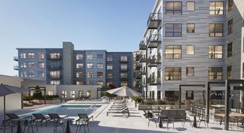 A modern apartment complex with a pool and outdoor seating area.