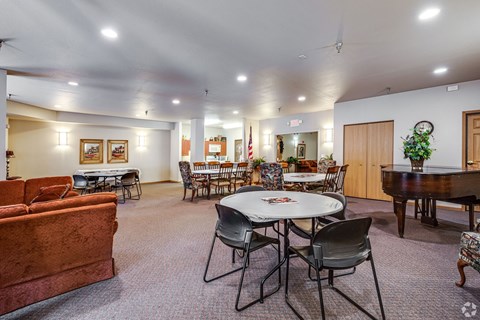 A room with a piano, chairs, and a dining table.
