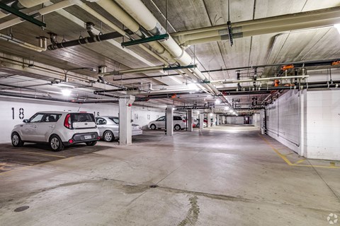 A parking garage with two cars parked in it.