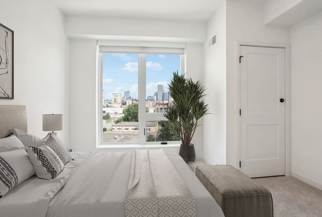 A bedroom with a large bed and a view of the city.
