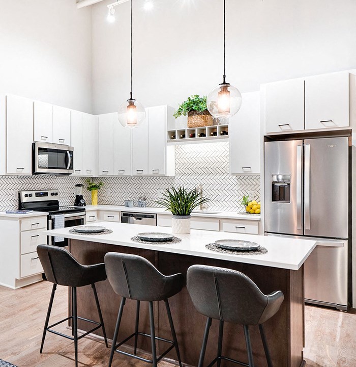 a kitchen with white cabinets and a large island with three stools