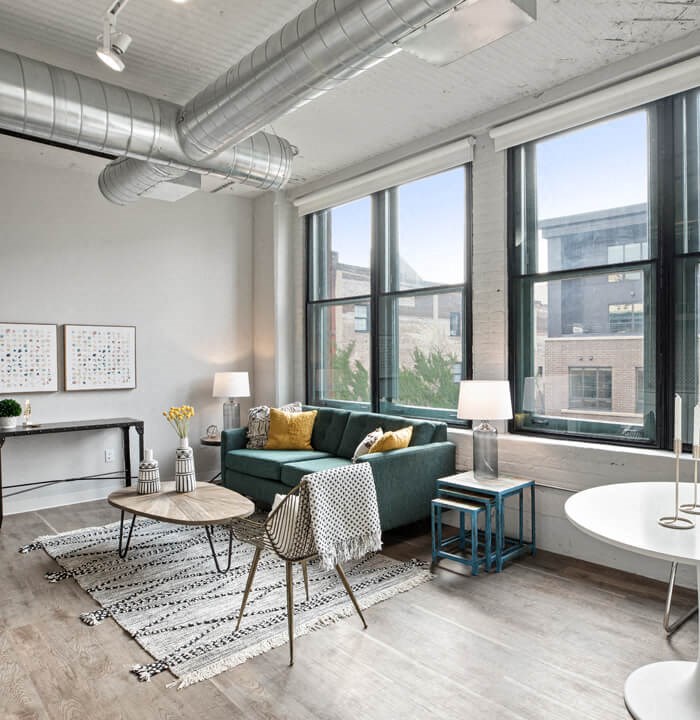 a living room with large windows and a green couch