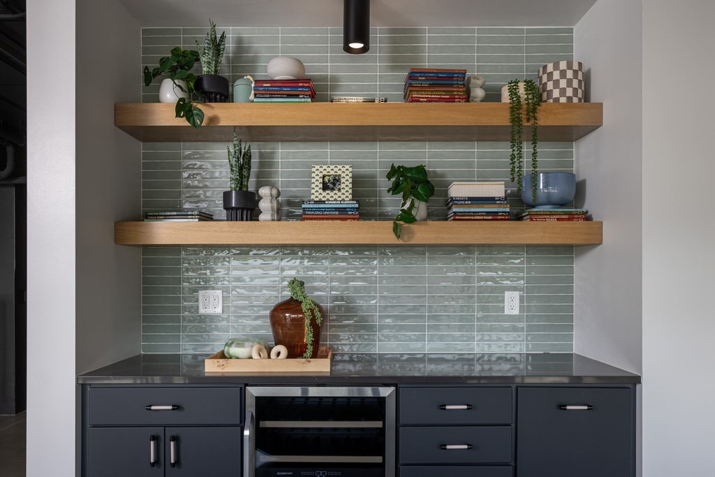 A kitchen with a tile backsplash and wooden shelves above the counter.
