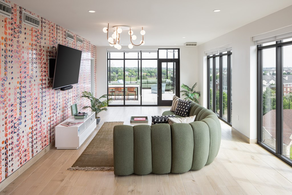A living room with a green couch and a television on the wall.