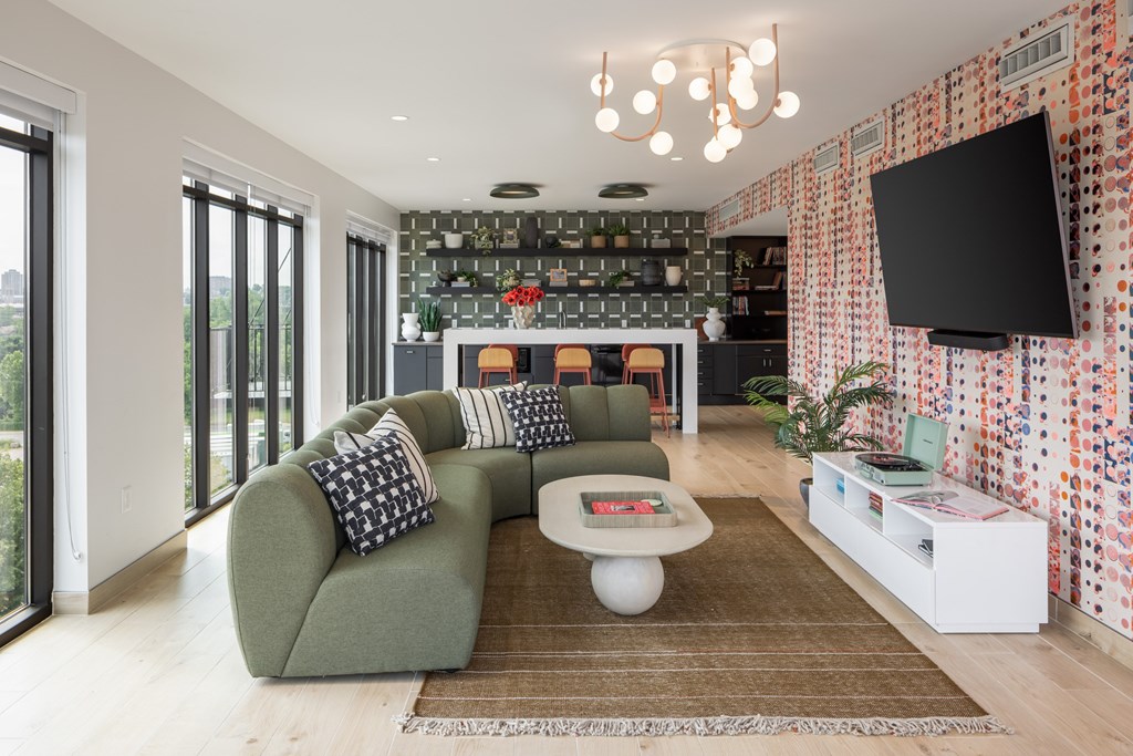 A modern living room with a green sofa and a patterned wallpaper.