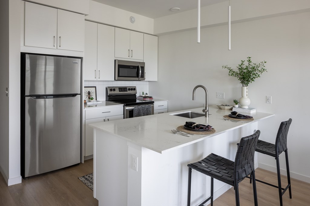 A kitchen with a white counter and a black chair.