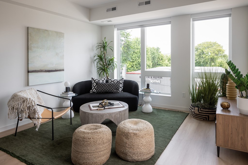 A living room with a black couch, a coffee table, and a green rug.