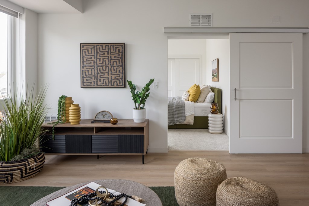 A living room with a brown and white cabinet, a green rug, and a large abstract painting on the wall.