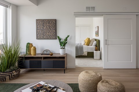 A living room with a brown and white cabinet, a green rug, and a large abstract painting on the wall.