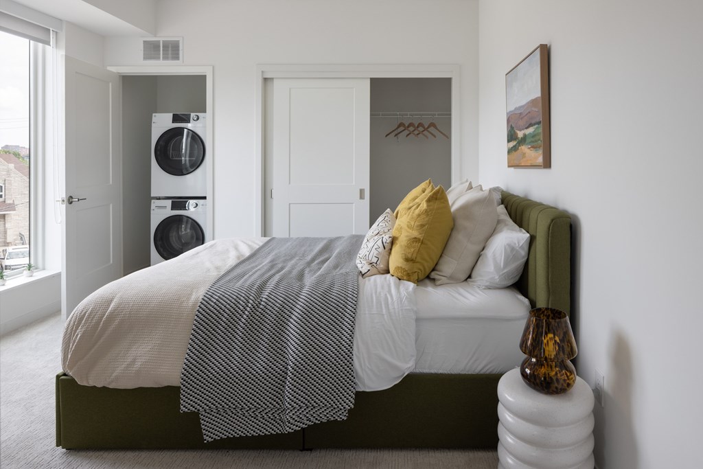 A bed with a white comforter and a green pillow is in the room.