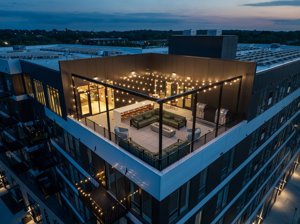 A modern building with a rooftop patio illuminated by string lights.
