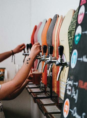 a group of people drinking beer next to a row of surfboards