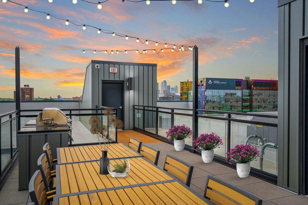 a rooftop terrace with a table and a view of the city and a sunset