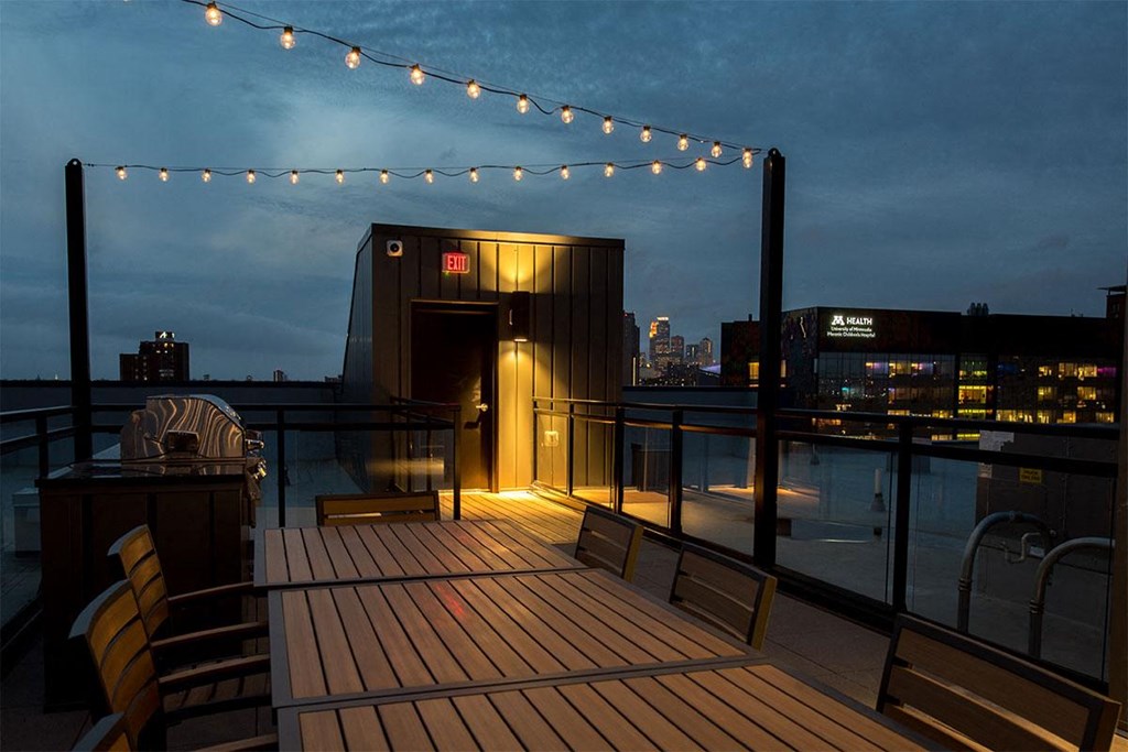 the roof terrace at night with lights and a view of the city