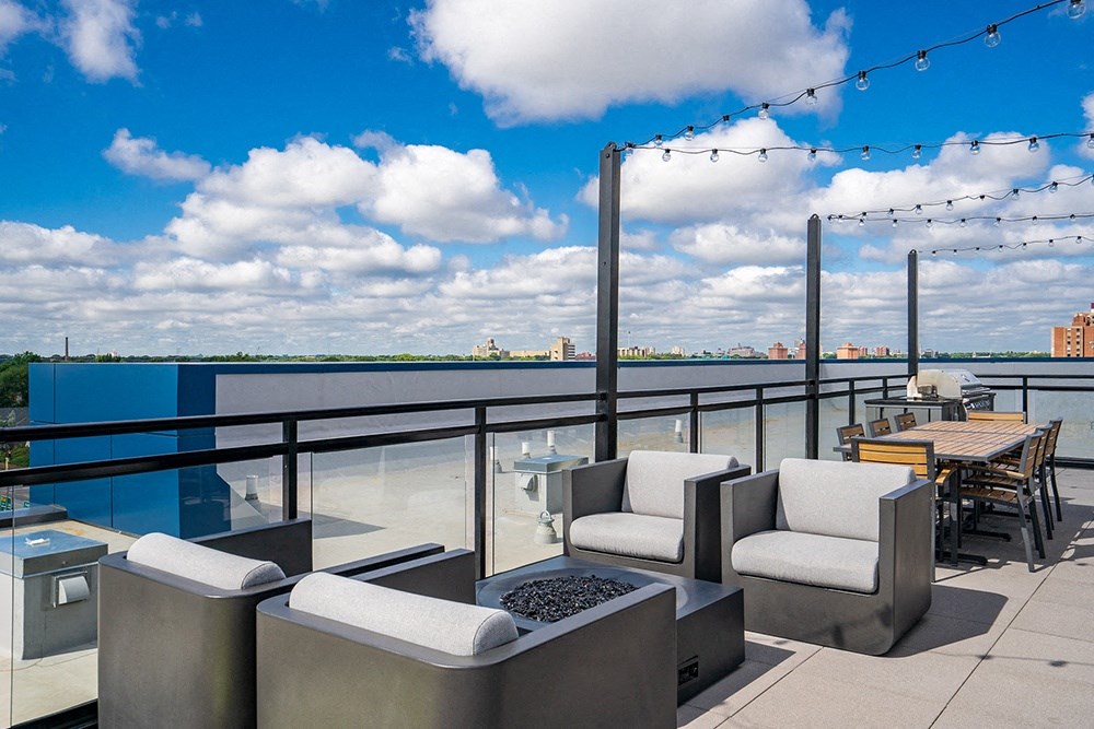 a rooftop terrace with a view of the water and chairs and tables