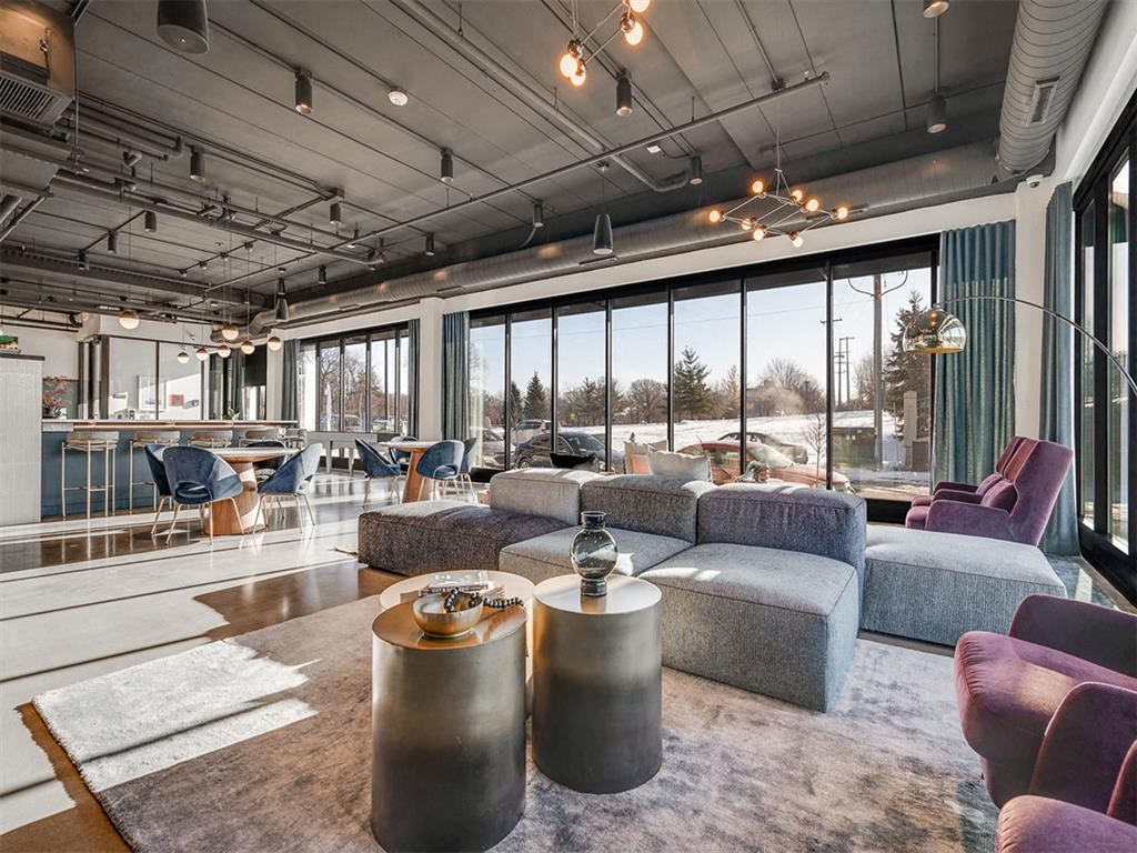 a living room with couches and chairs and large windows