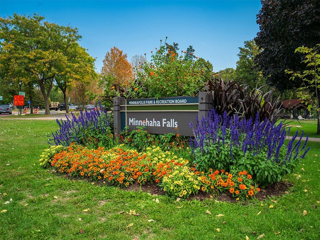 a sign falls in front of a garden of flowers