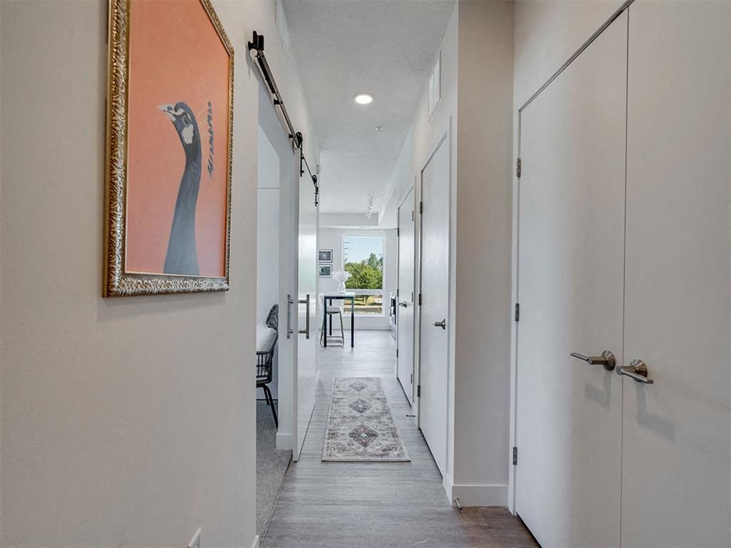 a long hallway with white doors and a painting on the wall