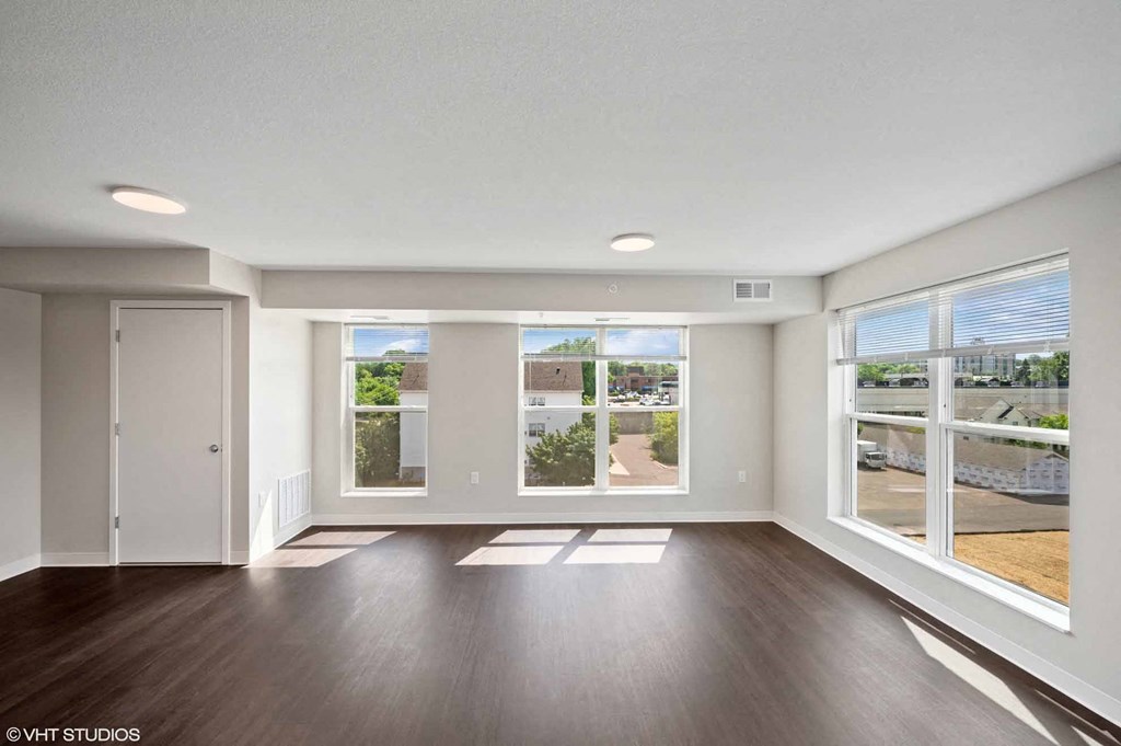 an empty living room with large windows and wood floors