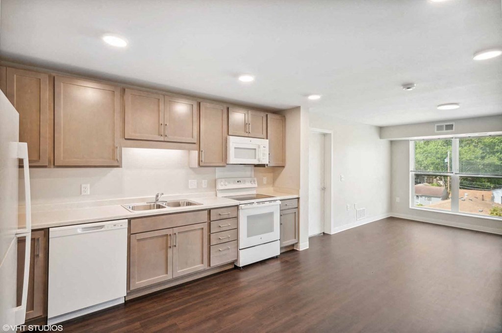 an empty kitchen with wooden floors and white appliances
