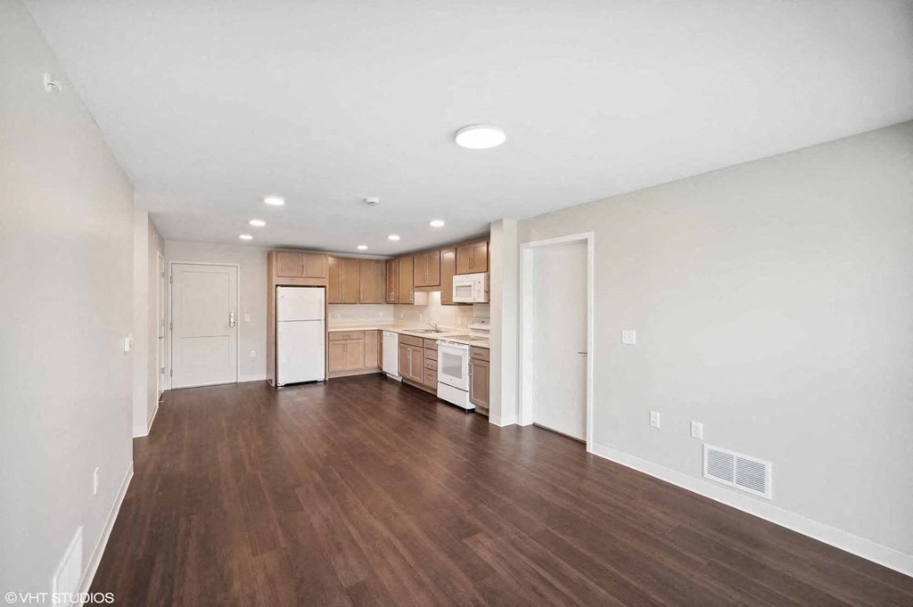 an empty living room and kitchen with wood flooring
