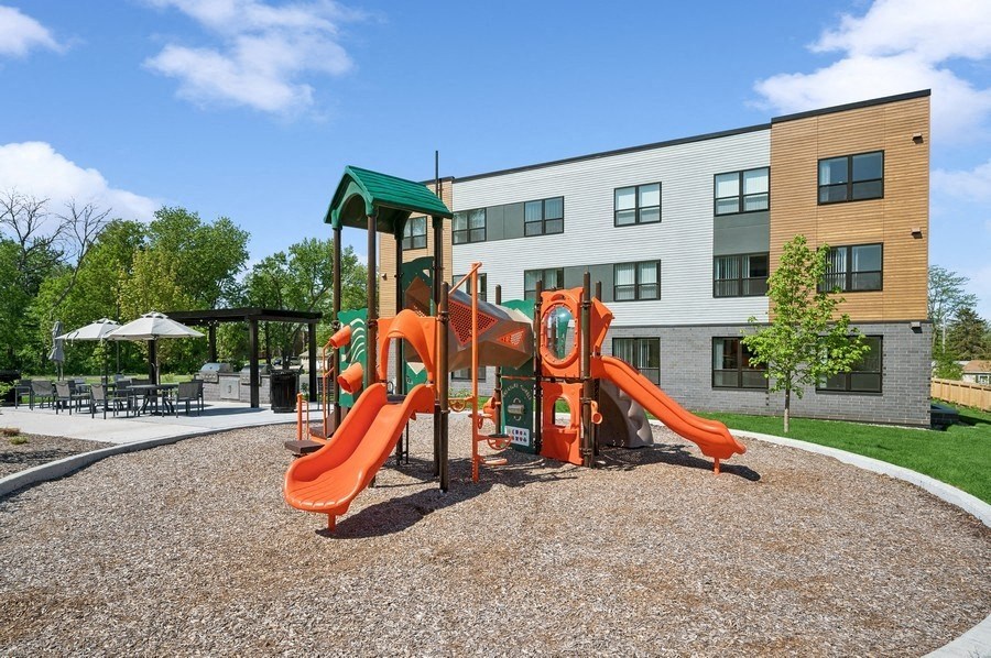 A playground with a red slide and a green roof.