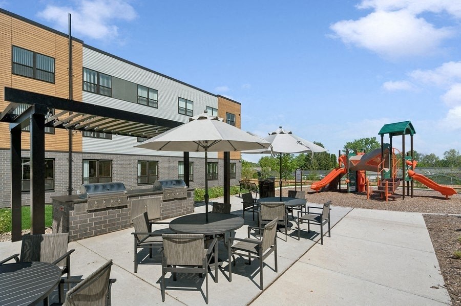 A playground with a slide and a building in the background.