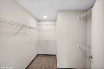 a walk in closet with white walls and shelves and a white closet door
