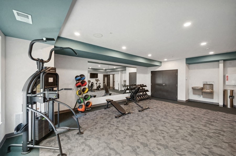 A gym with a variety of equipment including a treadmill, weights, and a bench.