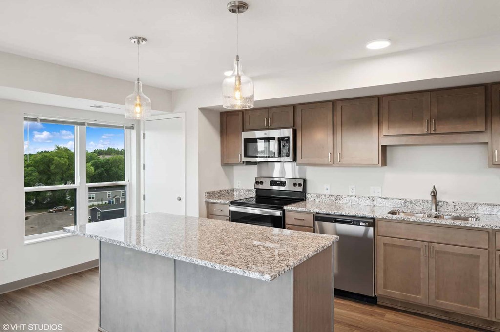 A modern kitchen with a granite countertop and stainless steel appliances.