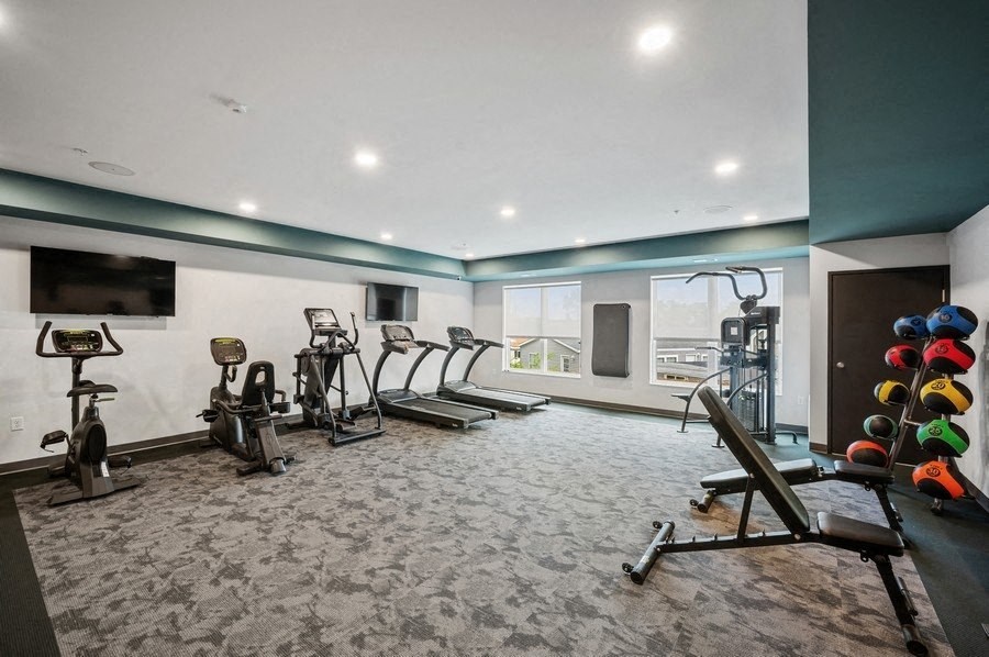 A spacious gym with a variety of exercise equipment including treadmills, stationary bikes, and weight racks.