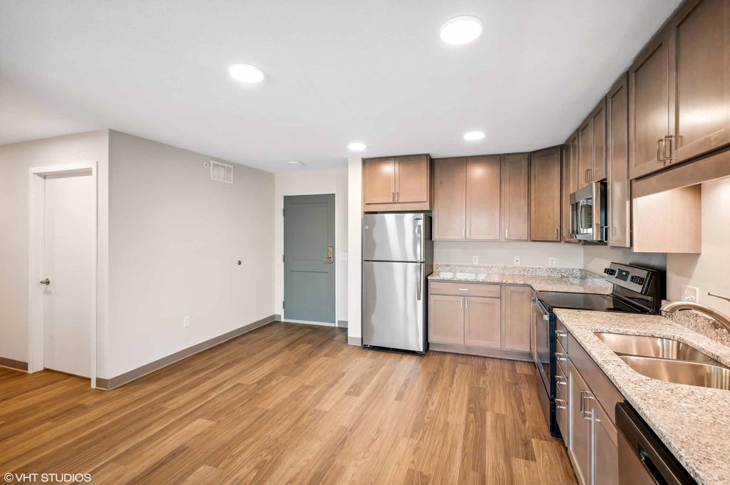 A kitchen with wooden floors and a stainless steel refrigerator.