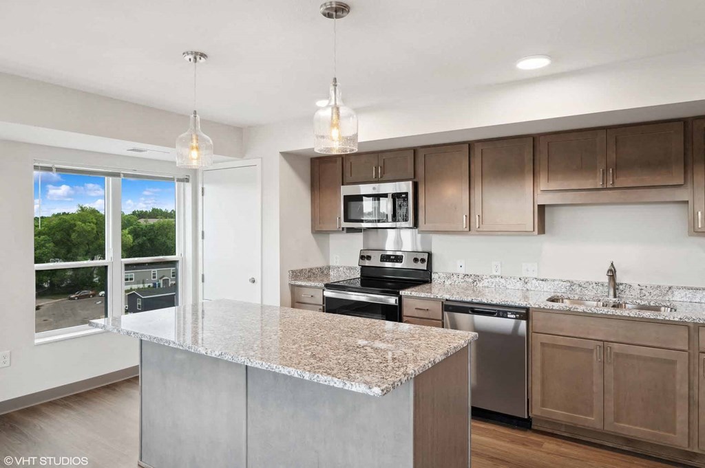 A kitchen with a granite countertop and stainless steel appliances.