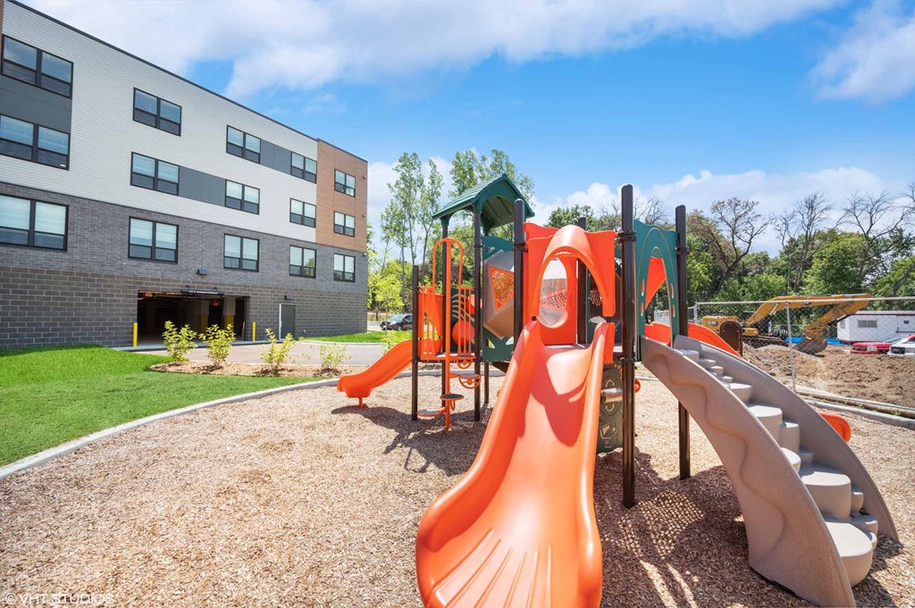 A playground with a red slide and a green roofed structure.