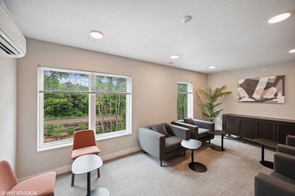 A living room with a large window and a view of trees and a building.