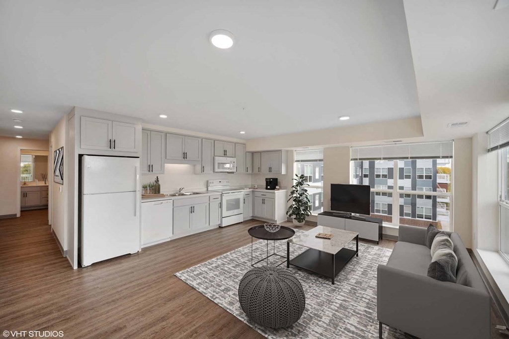 A modern kitchen with white appliances and a dining area with a round table and chairs.