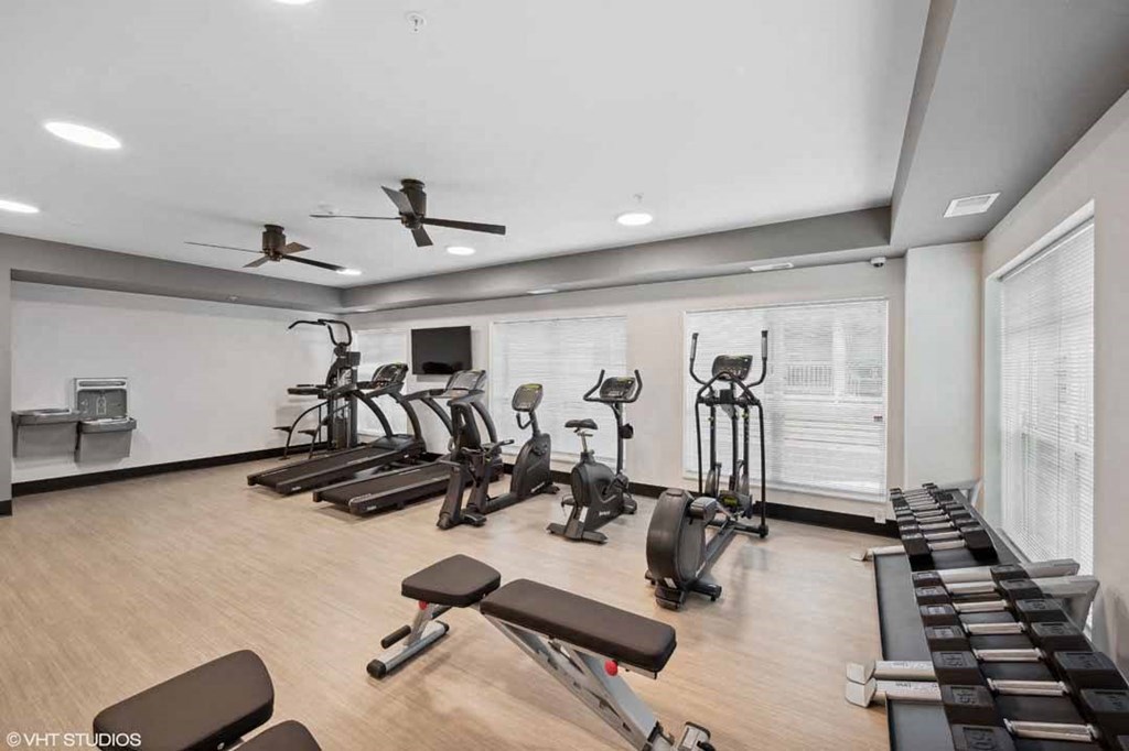 A spacious gym with a variety of equipment including treadmills, stationary bikes, and weight machines.