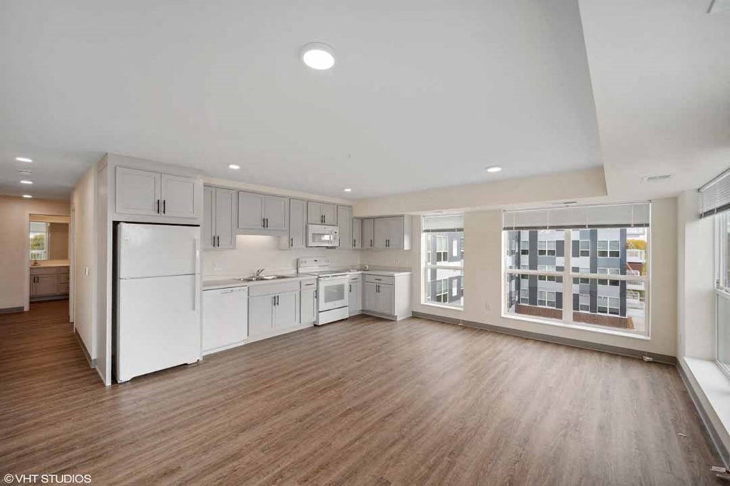 A spacious kitchen with white appliances and wooden floors.