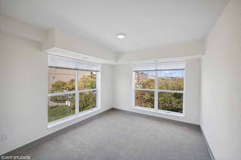 an empty living room with three windows in it