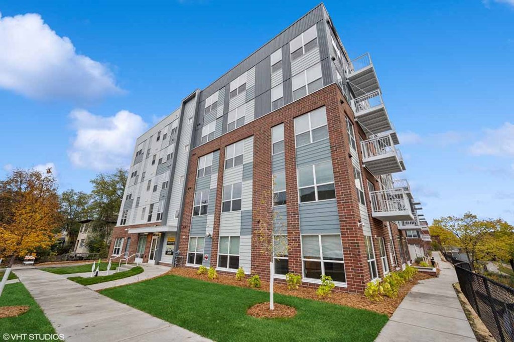 A modern multi-story apartment building with a mix of brick and panel siding.