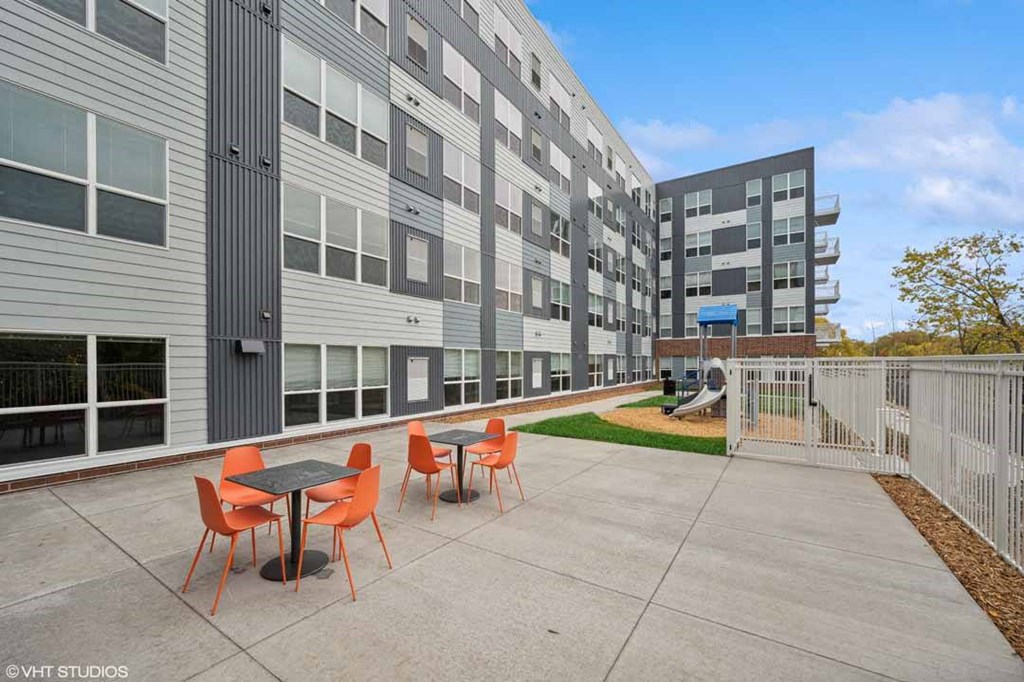 A patio with a table and chairs is in front of a building.