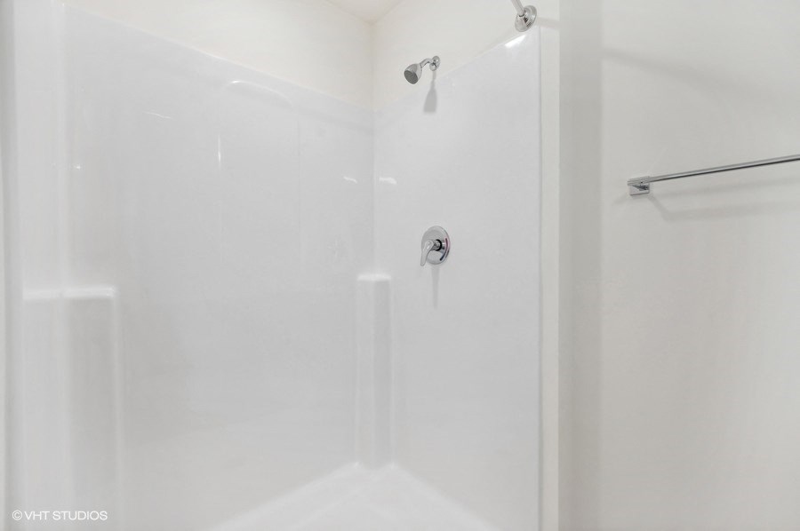 A white shower stall with a glass door and a shower head.